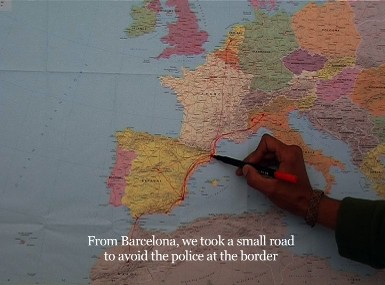 Une main tient un marqueur rouge et trace une ligne sur une carte du monde entre l'Espagne et la France. La ligne zigzague entre plusieurs pays européens et africains.
